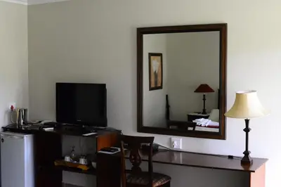a room with a desk with a television and a mirror at Avant Garde Lodge in Kempton Park