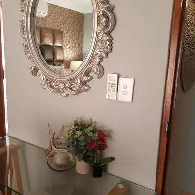 a mirror on a wall next to a table with flowers at Dinaledi House in Bela-Bela