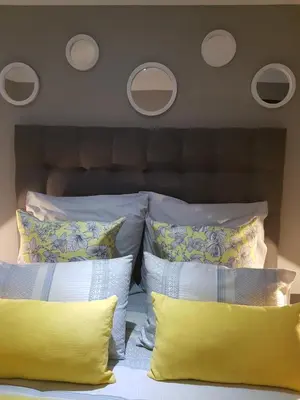 a bed with yellow and white pillows on it at Dinaledi House in Bela-Bela