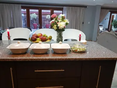 a counter with three bowls of fruit and a vase of flowers at Dinaledi House in Bela-Bela