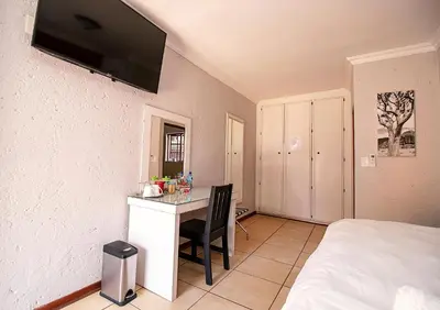 a bedroom with a desk and a bed and a room at The Doors Inn in Mokopane