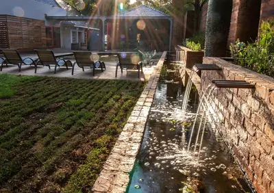 a pond in a yard with a fountain at The Doors Inn in Mokopane