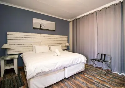 a bedroom with a large white bed and a chair at The Doors Inn in Mokopane