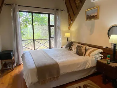 a bedroom with a bed and a large window at Buster's River Lodge in Marloth Park