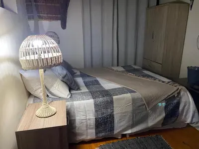 a bedroom with a bed with a bird cage on a table at Buster's River Lodge in Marloth Park