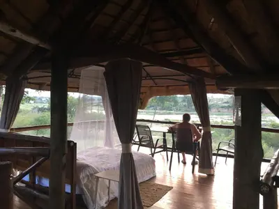 a man sitting at a table in a room with a bed at Buster's River Lodge in Marloth Park