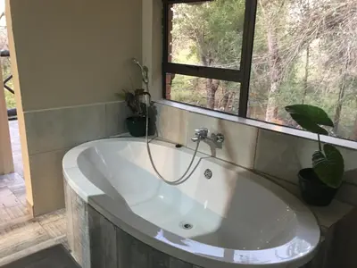 a bath tub in a bathroom with a window at Buster's River Lodge in Marloth Park