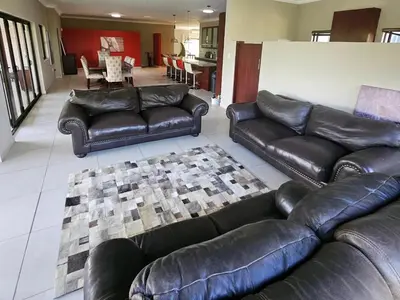 a living room with black leather couches and a table at Bokmakierie Place in Modimolle