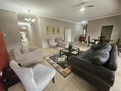a living room with a black leather couch and chairs at Bokmakierie Place in Modimolle