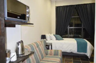 a hotel room with a bed and a chair at Birrea Guest house in Polokwane