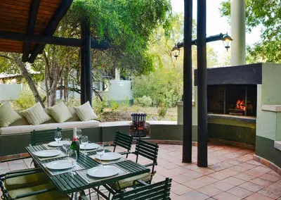 a patio with a table and chairs and a fireplace at Burchell's Bush Lodge by Dream Resorts in Sabi Sand Game Reserve