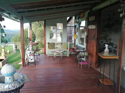 a porch with chairs and tables on a house at House of Art in Haenertsburg