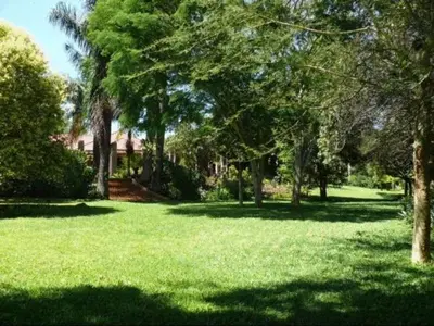 a field of green grass with trees and a house at Ku De Ta B&B in White River