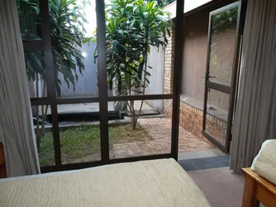 a bedroom with a view of a garden through a glass door at Ku De Ta B&B in White River