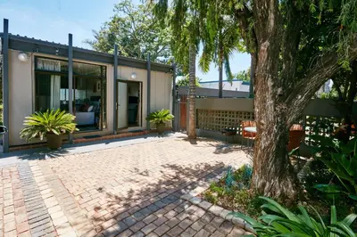 a house with a tree and a brick patio at 1202 on Cowgill in Pretoria