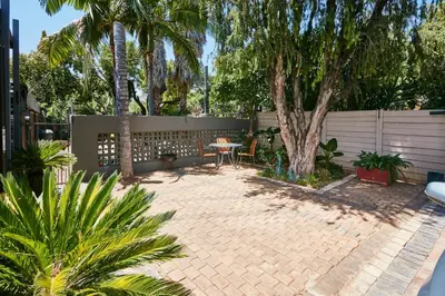 a patio with a table and a fence and palm trees at 1202 on Cowgill in Pretoria