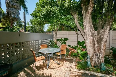 a patio with a table and chairs next to a tree at 1202 on Cowgill in Pretoria