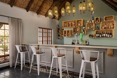 a bar with white stools in a room at Premier Hotel Roodevalley in Pretoria