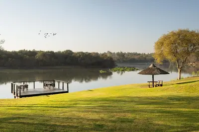 a dock with benches and tables on a lake at Premier Hotel Roodevalley in Pretoria