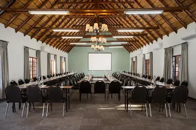a large room with tables and chairs and a screen at Premier Hotel Roodevalley in Pretoria