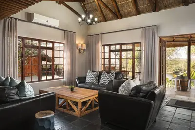 a living room with leather couches and a wooden table at Premier Hotel Roodevalley in Pretoria