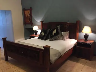 a bedroom with a large wooden bed with two lamps at Baobab Lane Lodge in Marnitz