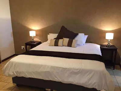 a bedroom with a large white bed with two lamps at Baobab Lane Lodge in Marnitz
