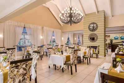 a restaurant with tables and chairs and a chandelier at Protea Hotel by Marriott Nelspruit in Nelspruit