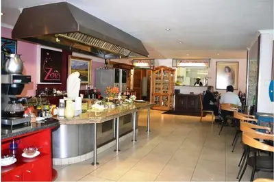 a kitchen with people sitting at tables in a restaurant at Brooklyn Lodge in Pretoria