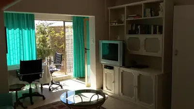 a living room with a television and a table and a window at Brooklyn Lodge in Pretoria