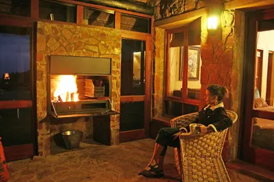 a man sitting in a chair in front of a fireplace at Verlorenkloof in Dullstroom
