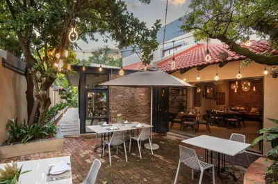 an outdoor patio with tables and chairs and a restaurant at Opikopi Guest House in Pretoria