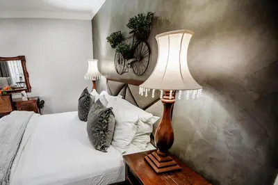 a bedroom with a bed and a table with a lamp at Opikopi Guest House in Pretoria