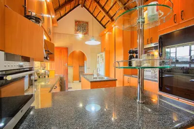 a large kitchen with wooden cabinets and black counter tops at All over Africa Guest house in Kempton Park