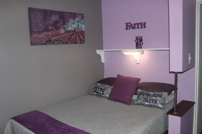a small bedroom with a bed with purple walls at PhysEQFiT Guesthouse & Spa in Centurion
