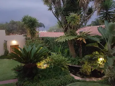 a garden in front of a house with palm trees at PhysEQFiT Guesthouse & Spa in Centurion