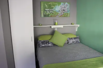 a small bedroom with a bed with green pillows at PhysEQFiT Guesthouse & Spa in Centurion