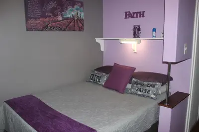 a small bedroom with a bed with purple walls at PhysEQFiT Guesthouse & Spa in Centurion