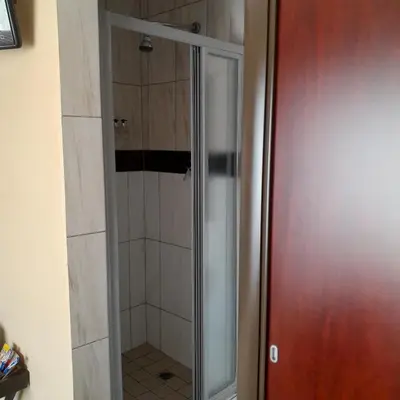 a shower with a glass door in a bathroom at The Shamrock Hotel in Polokwane