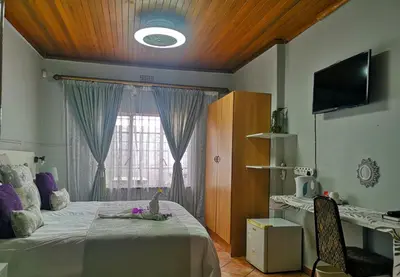 a bedroom with a bed and a tv and a window at Elsjes Guesthouse in Kempton Park