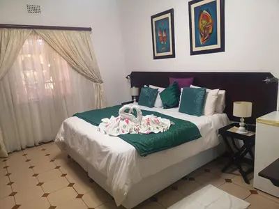 a bedroom with a bed with green and white sheets at Elsjes Guesthouse in Kempton Park
