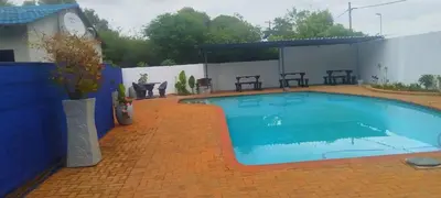 a swimming pool with a clock on the side of a house at Elsjes Guesthouse in Kempton Park