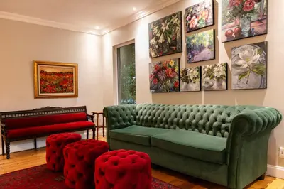 a living room with a green couch and some paintings at Murray Street 137 Guesthouse in Pretoria