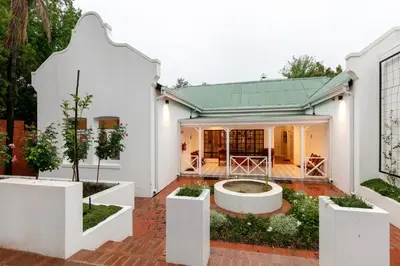 a white house with a courtyard with trees at Murray Street 137 Guesthouse in Pretoria