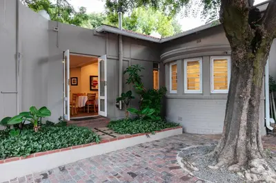 a house with a tree in front of it at Murray Street 137 Guesthouse in Pretoria