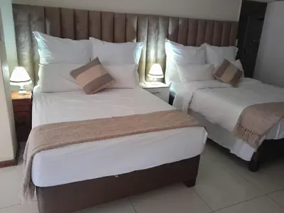 two beds in a hotel room with two lamps at Purple Olive Guest House in Pretoria