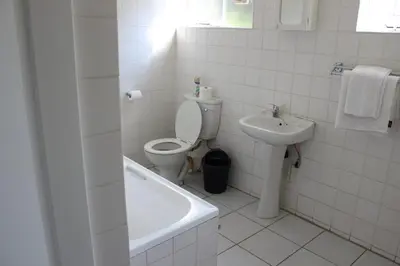 a white bathroom with a toilet and a sink at Purple Olive Guest House in Pretoria