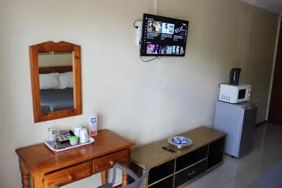 a room with a table and a mirror and a refrigerator at Purple Olive Guest House in Pretoria