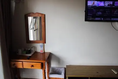 a wooden dresser with a mirror and a desk at Purple Olive Guest House in Pretoria