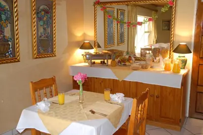 a dining room with a table with white table cloth at Purple Olive Guest House in Pretoria